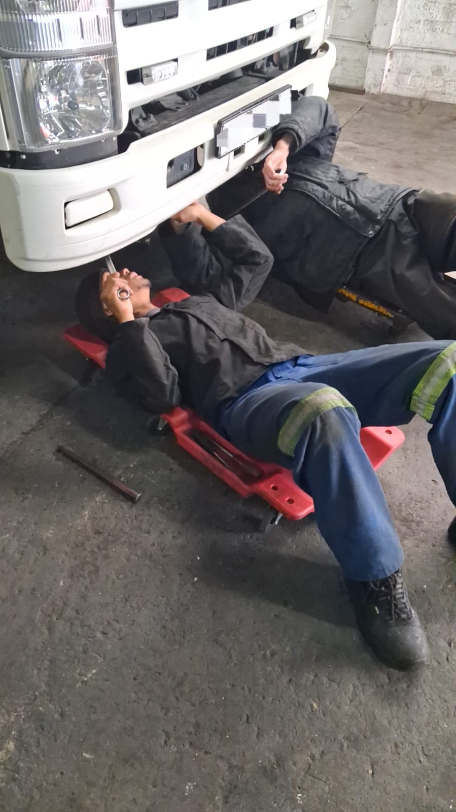 DTL mechanic working under the front of an Isuzu truck
