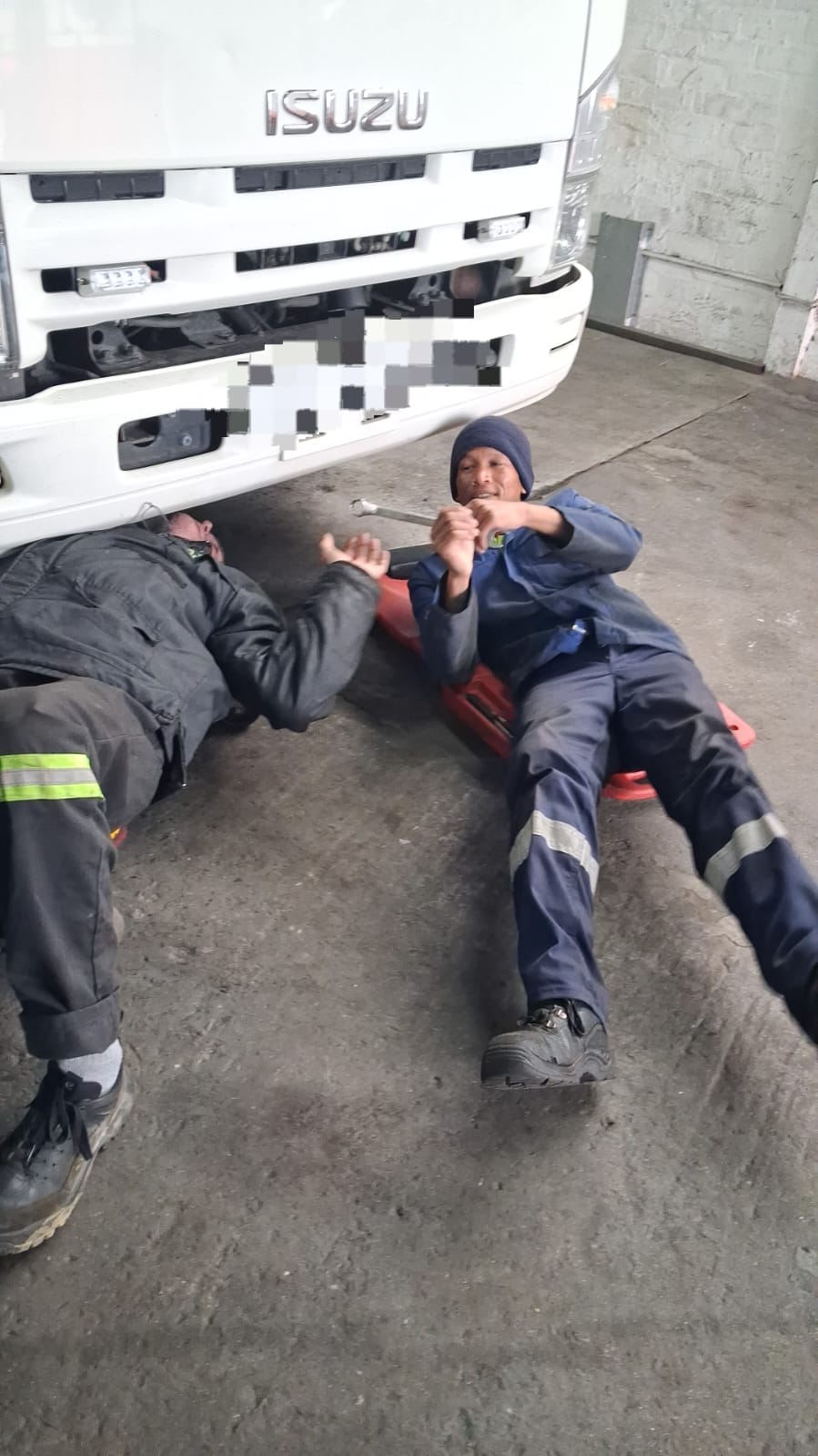 DTL mechanic working underneath a truck on a creeper board