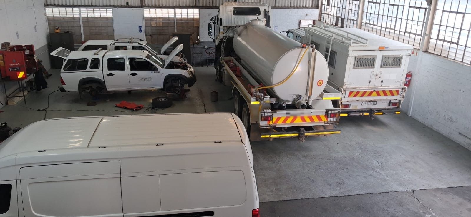 Trucks, a water tanker and light vehicles inside the DTL Mechanical Repairs workshop